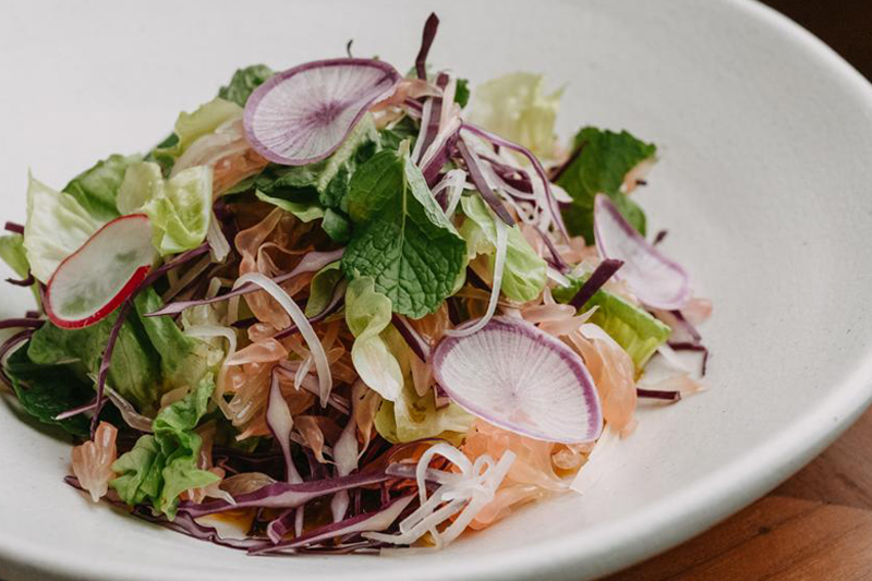 A vibrant Pomelo salad, at HOME by Chef Wayan, showcasing a medley of fresh greens, radish, and juicy pomelo bits